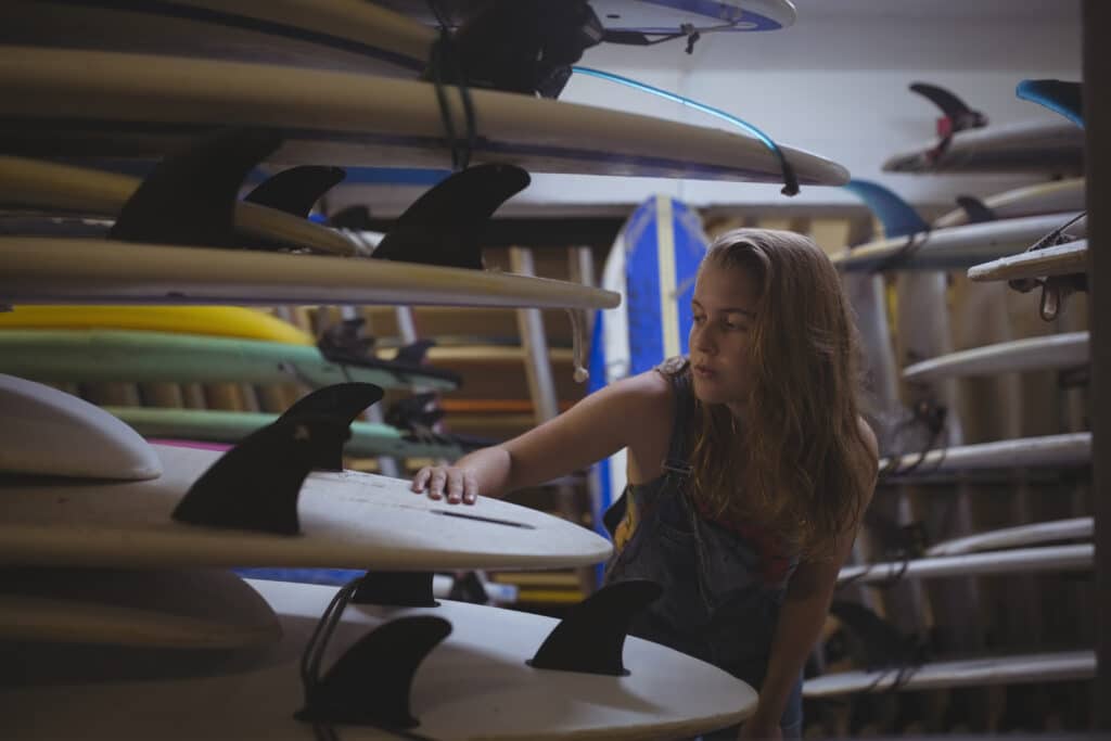 Woman selecting a surfboard in beach cabin