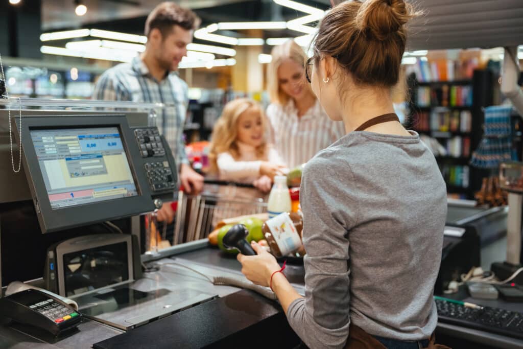 Beautiful family standing at the cash counter buying groceries with a barcode scanner
